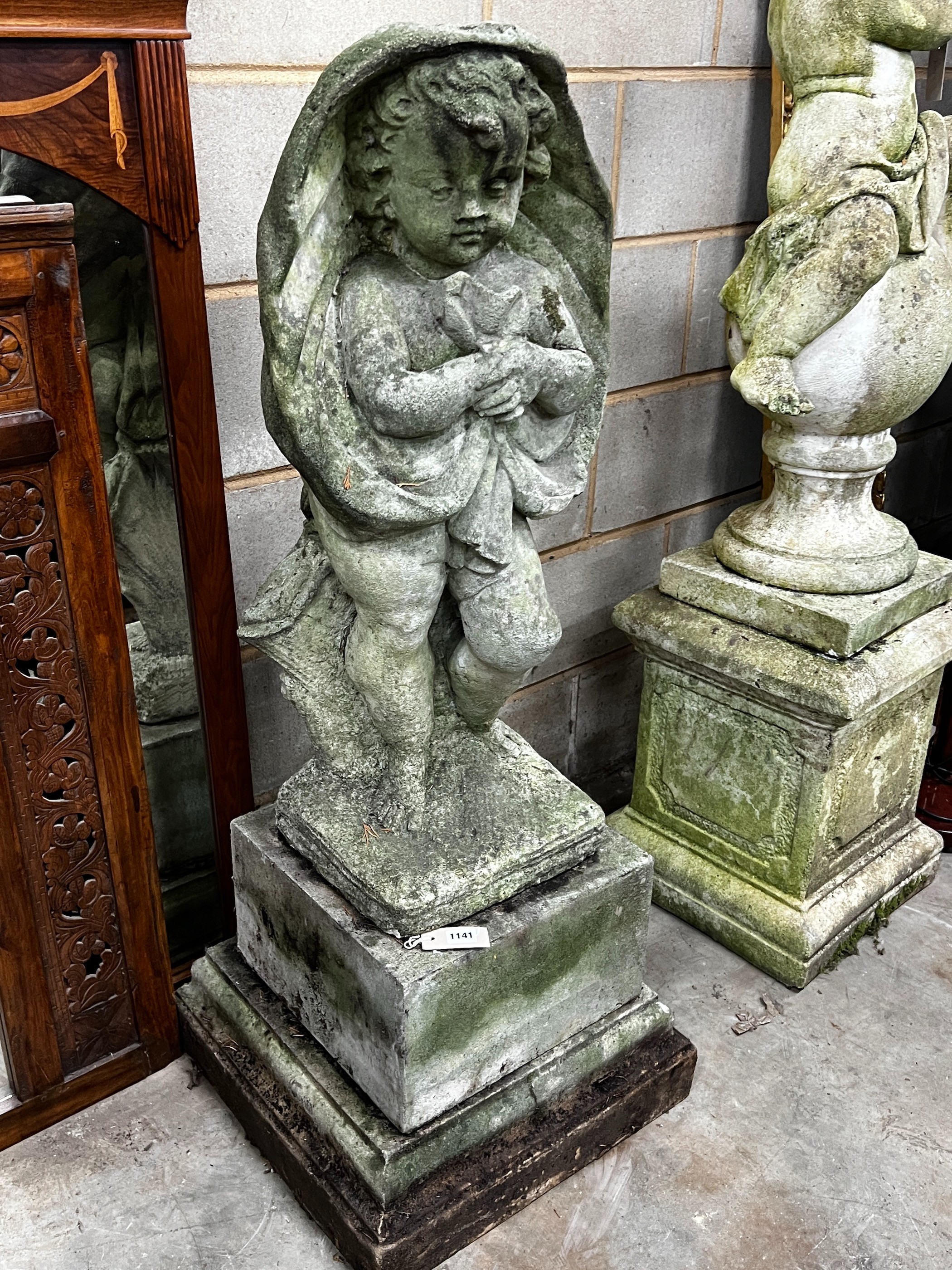 A large weathered reconstituted stone garden figure, cherub in drapery, height 122cm